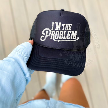 A person is holding a black baseball cap with the text
